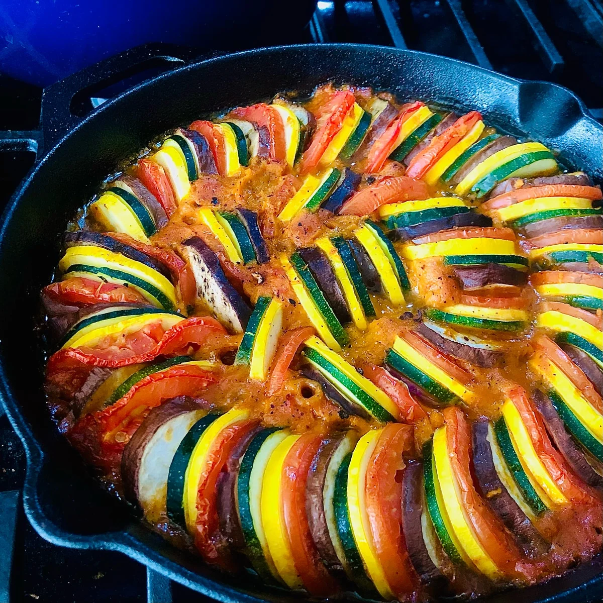 Colourful vegetable slices arranged in curved rows in a cast-iron pan.